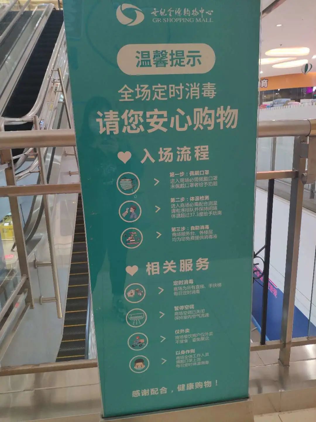 门口有专人值守,并配备自动测温仪,商场内部也有一些防疫指示牌和宣传